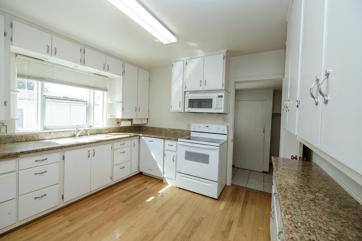 4541 North Gratton Road Denair, CA 95316 - Photo 24 of 75 a kitchen with granite countertop white cabinets and white appliances