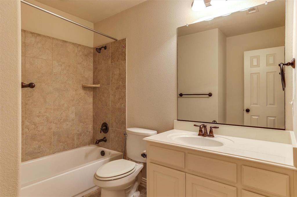 419 Rio Grande Drive Irving, TX 75039 - Photo 23 of 29 Bathroom featuring a single vanity with a white countertop and base cabinetry, a full-width mirror, and a tub-shower combination with tiled surround and bronze-finish fixtures