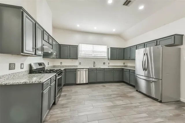 a kitchen with stainless steel appliances granite countertop a sink a stove a refrigerator and a sink