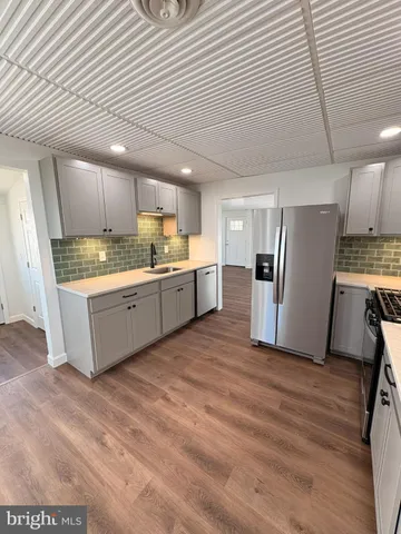 a kitchen with a sink a refrigerator and wooden floor