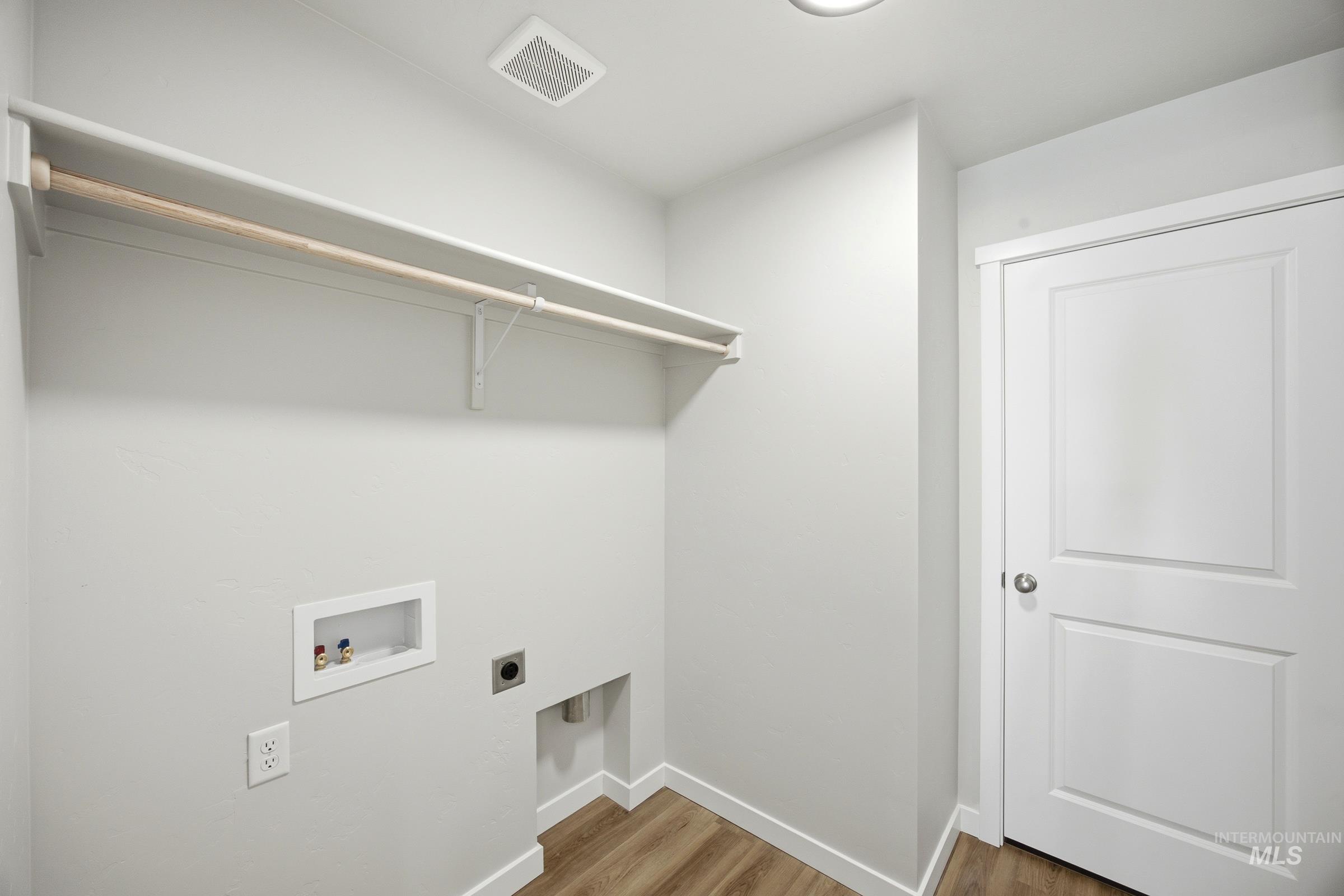 13333 Bank Street Caldwell, ID 83607 - Photo 24 of 29 Laundry area with wood-finish flooring, overhead shelving, and a built-in hanging rod