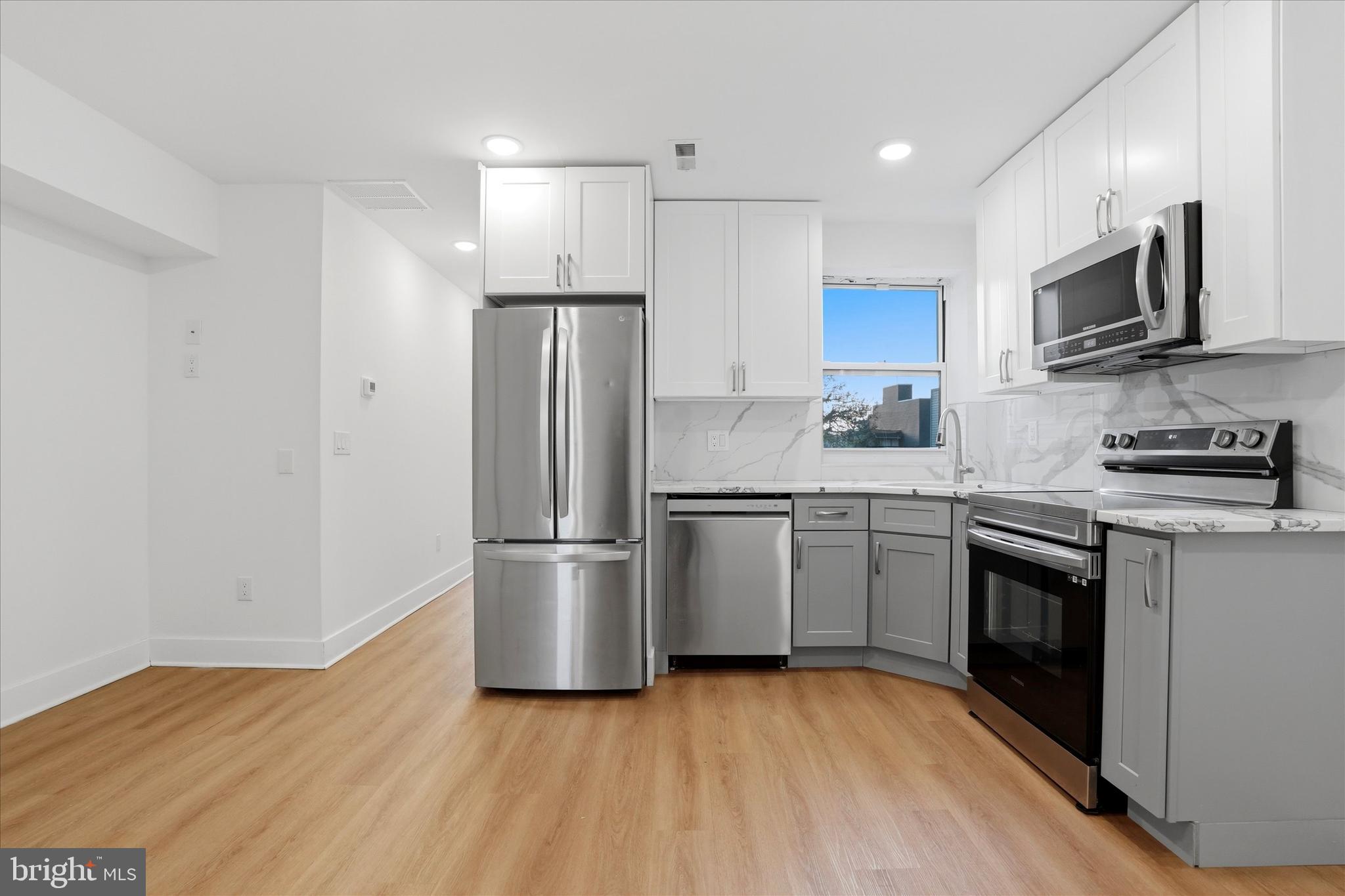 2104 North 8th Street, Unit 3 Philadelphia, PA 19122 - Photo 4 of 15 a kitchen with a sink a refrigerator a microwave and cabinets