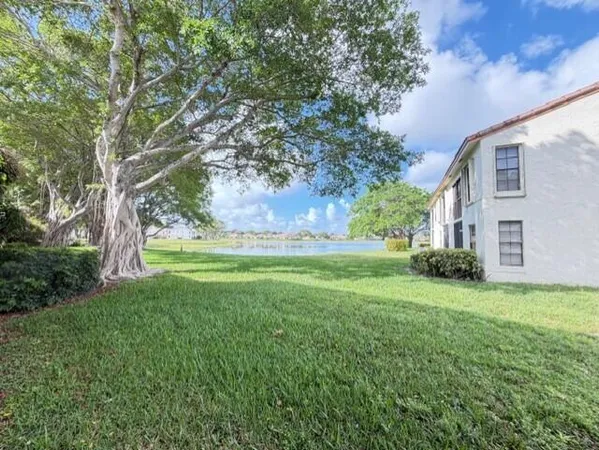 a view of a house with a big yard and large trees