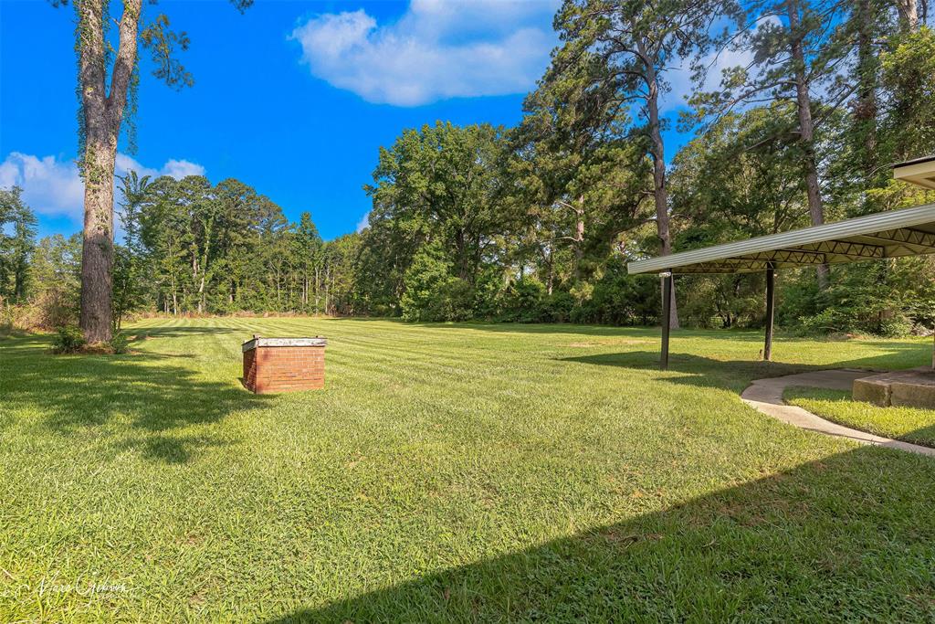 9342 Dean Road Shreveport, LA 71118 - Photo 3 of 18 Expansive grassy yard with mature trees and a brick-built feature