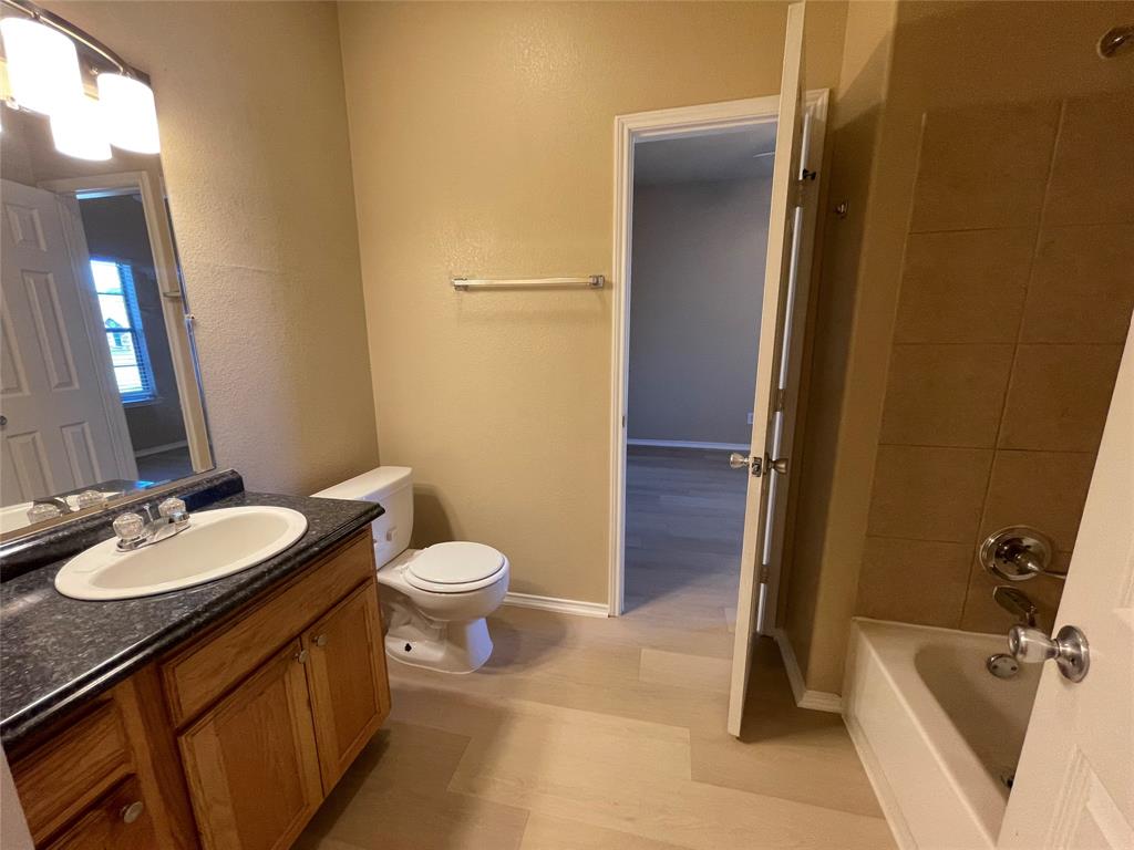 101 Sunburst Court, Unit 107 Weatherford, TX 76087 - Photo 13 of 24 a bathroom with a sink a toilet and tub