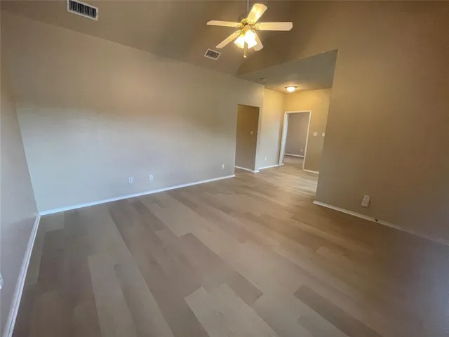 an empty room with a chandelier fan and closet area