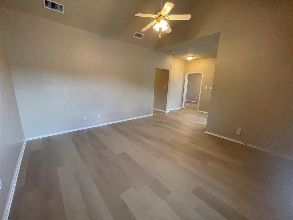 101 Sunburst Court, Unit 107 Weatherford, TX 76087 - Photo 3 of 24 an empty room with a chandelier fan and closet area