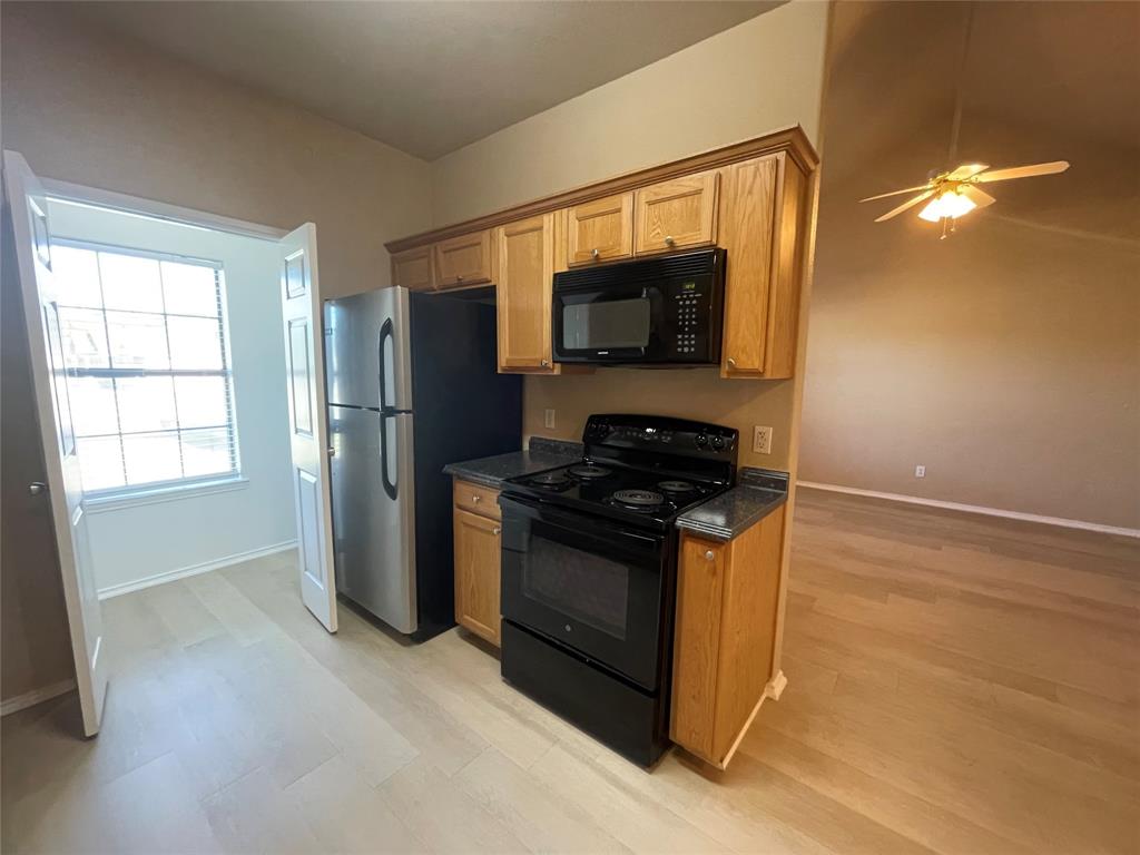 101 Sunburst Court, Unit 107 Weatherford, TX 76087 - Photo 4 of 24 a kitchen with stainless steel appliances a stove a microwave and a refrigerator