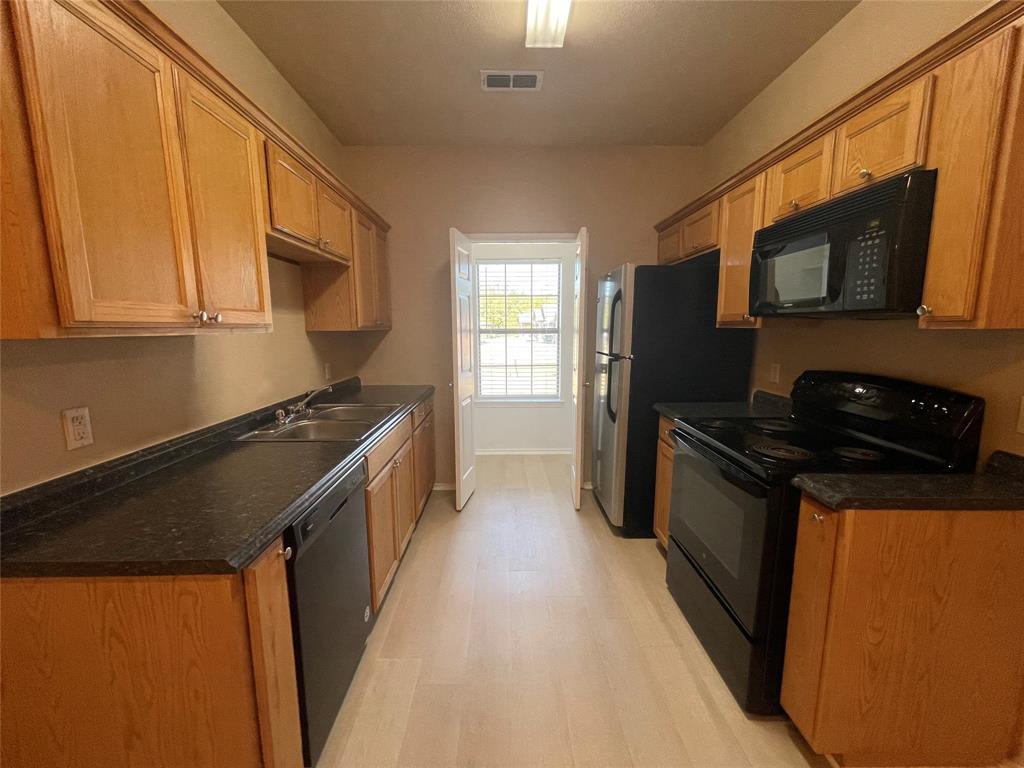 101 Sunburst Court, Unit 107 Weatherford, TX 76087 - Photo 5 of 24 a kitchen with stainless steel appliances granite countertop a stove a sink and a microwave