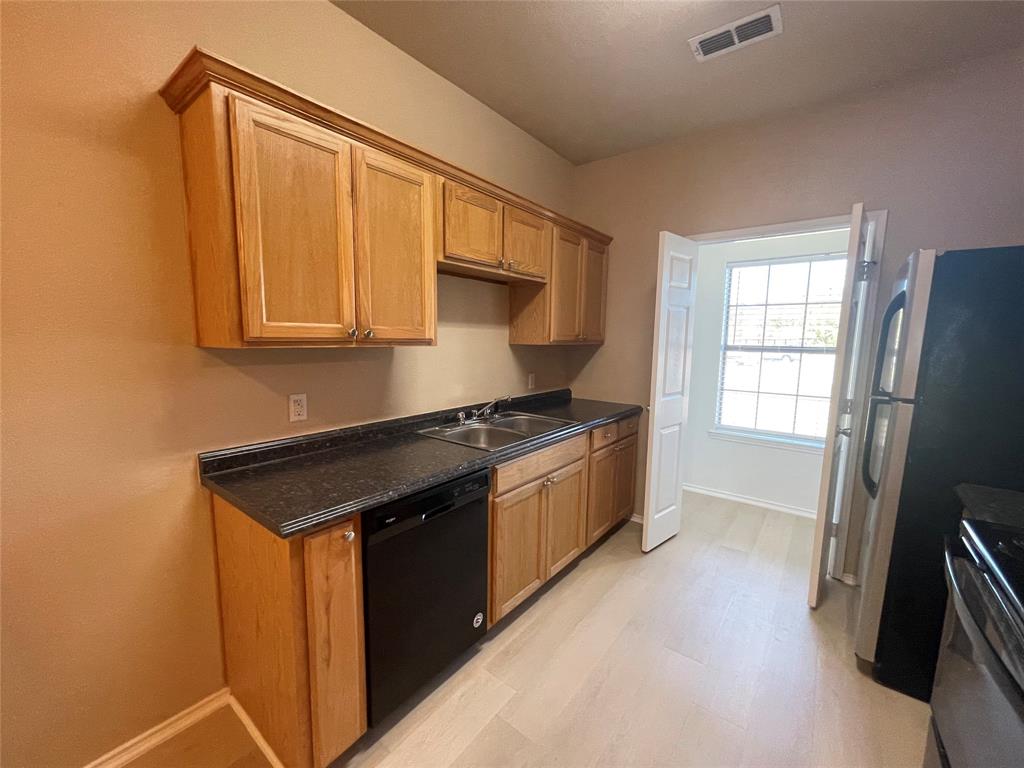 101 Sunburst Court, Unit 107 Weatherford, TX 76087 - Photo 6 of 24 a kitchen with stainless steel appliances granite countertop a stove a sink and a refrigerator