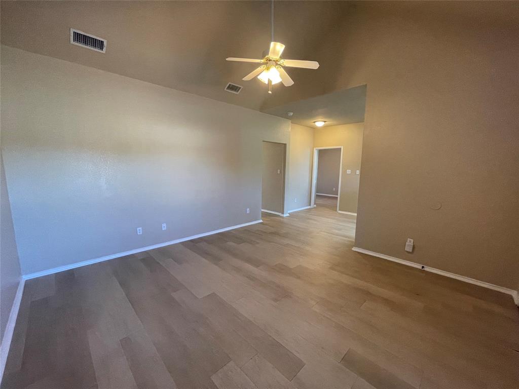 101 Sunburst Court, Unit 107 Weatherford, TX 76087 - Photo 8 of 24 an empty room with a chandelier fan and windows