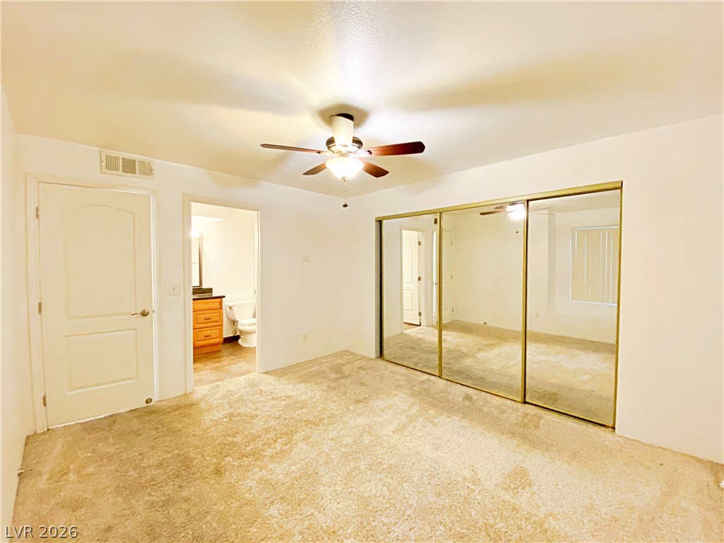 3145 East Flamingo Road, Unit 1128 Las Vegas, NV 89121 - Photo 14 of 19 Mirrored closet doors and a ceiling fan create a comfortable and practical bedroom environment.