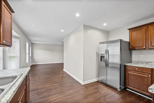 a kitchen with granite countertop a refrigerator and wooden cabinets