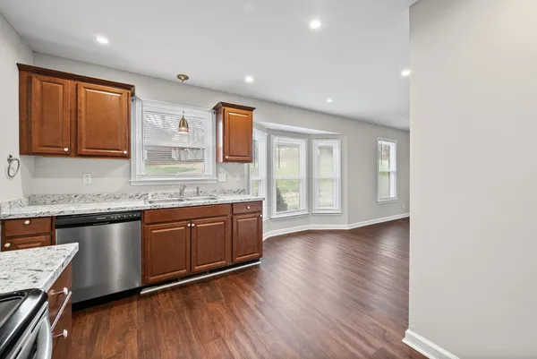 a kitchen with granite countertop wooden floors a sink and cabinets