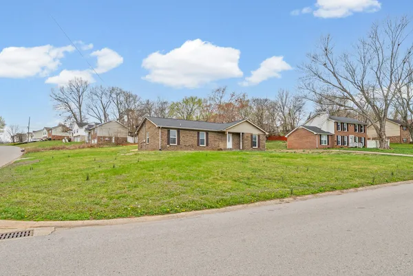 a view of a house with a big yard and large trees