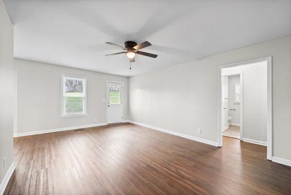 a view of an empty room with wooden floor and a window
