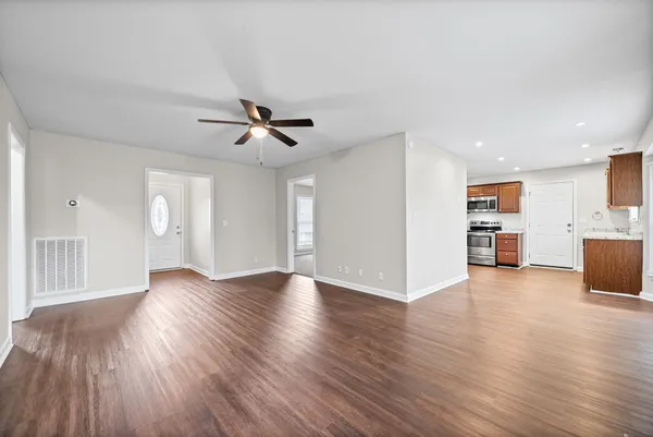 a view of an empty room with window and wooden floor