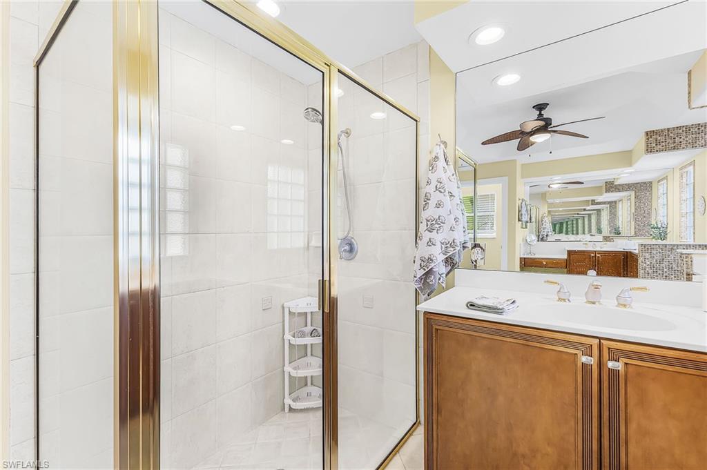 1415 Princess Sabal Point Naples, FL 34119 - Photo 21 of 42 Glass-enclosed shower with gold-tone framing and white tile surround