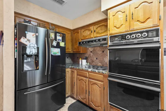 a large kitchen with stainless steel appliances granite countertop a stove a sink and a large window