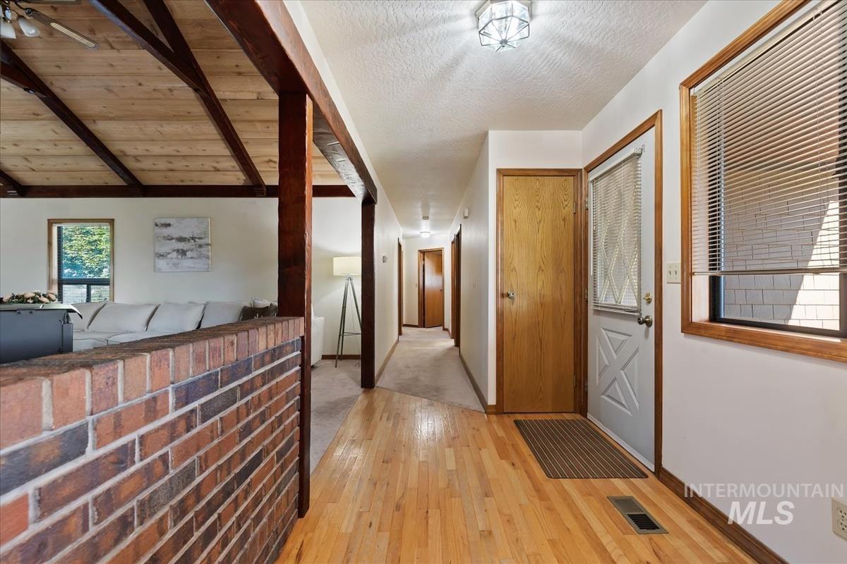 8275 Washoe Road Fruitland, ID 83619 - Photo 14 of 43 Hardwood flooring, exposed wood beam ceiling, brick half-wall, and a solid wood door