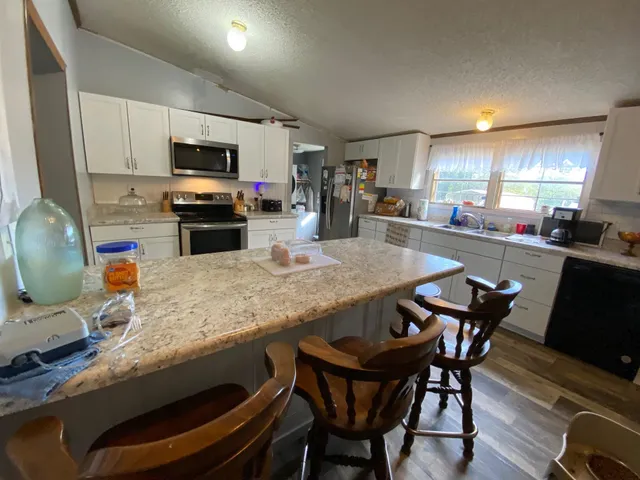 a kitchen with stainless steel appliances granite countertop a table chairs sink and microwave