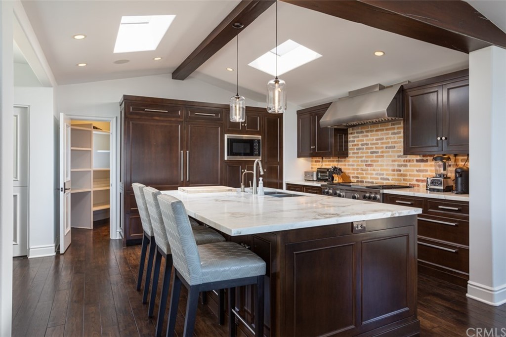 841 Emerald Bay Laguna Beach, CA 92651 - Photo 11 of 31 a kitchen with stainless steel appliances kitchen island granite countertop a table chairs sink and cabinets
