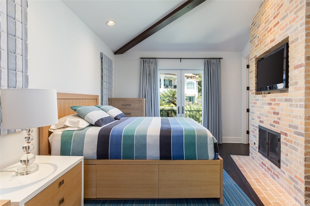 841 Emerald Bay Laguna Beach, CA 92651 - Photo 22 of 31 a bedroom with a bed a fireplace and a flat screen tv