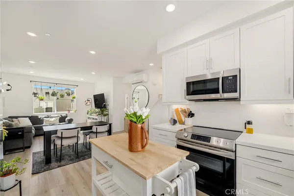 a kitchen with stainless steel appliances granite countertop a stove top oven a sink a dining table and chairs with white cabinets