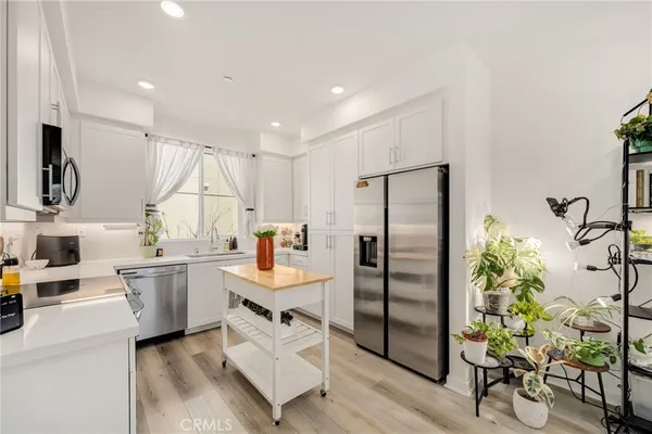 a kitchen with stainless steel appliances a refrigerator a sink a stove and white cabinets