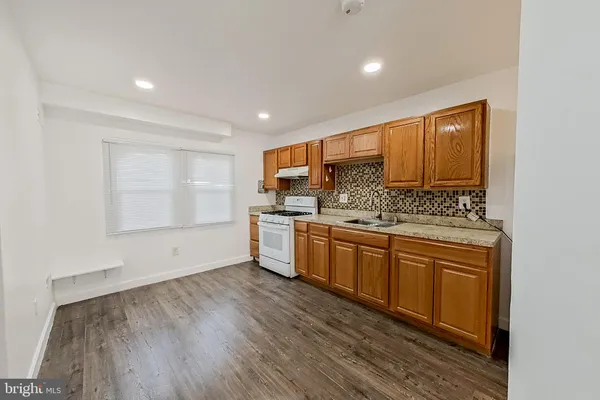 a kitchen with stainless steel appliances granite countertop a sink cabinets and wooden floor