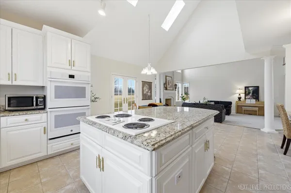 a kitchen with granite countertop white cabinets and white appliances