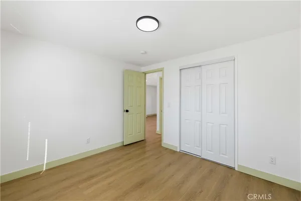 a view of an empty room with wooden floor and fan