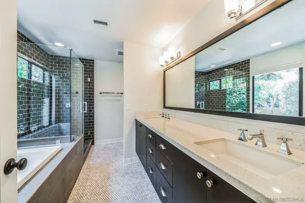 a bathroom with a granite countertop sink mirror double vanity and bathtub