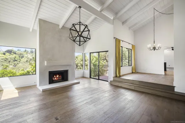 an empty room with wooden floor a fireplace and windows