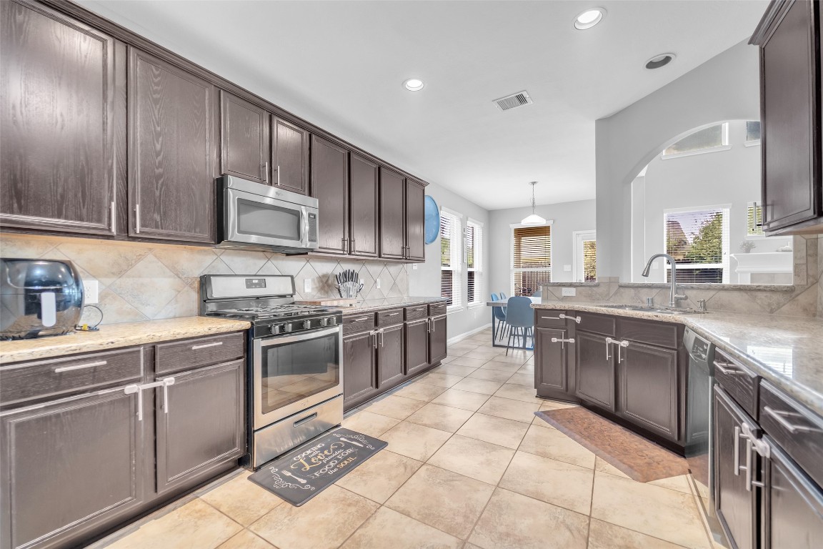 1230 Maple Ace Drive Katy, TX 77493 - Photo 11 of 40 a large kitchen with stainless steel appliances granite countertop a stove granite counter tops and white cabinets