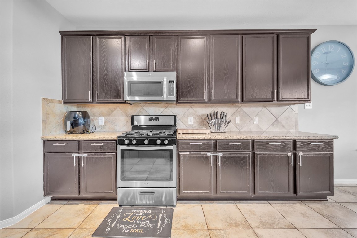 1230 Maple Ace Drive Katy, TX 77493 - Photo 14 of 40 a kitchen with stainless steel appliances granite countertop a stove a microwave and a sink