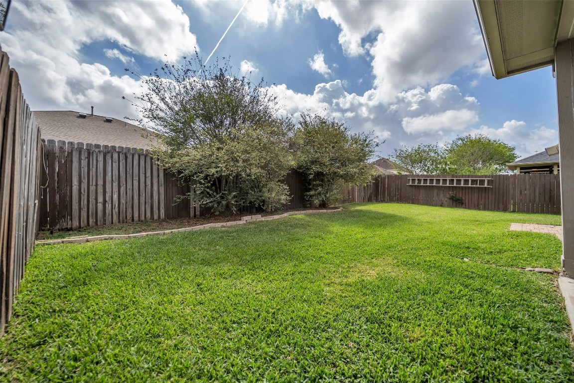 1230 Maple Ace Drive Katy, TX 77493 - Photo 38 of 40 Spacious backyard with lush grass, mature trees, and a wooden privacy fence, perfect for outdoor activities and relaxation.