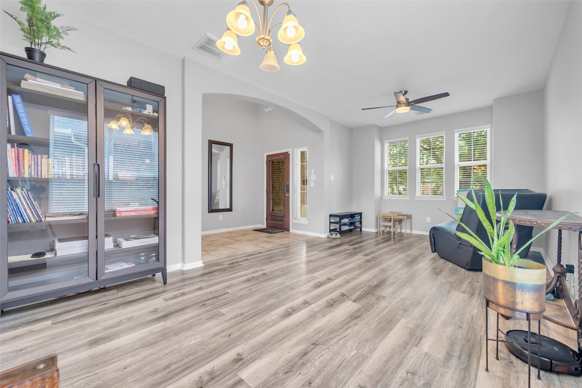1230 Maple Ace Drive Katy, TX 77493 - Photo 7 of 40 Bright and spacious living area with modern laminated wood flooring, large windows for natural light, and a cozy seating arrangement. Features a ceiling fan, decorative lighting, and a stylish bookcase.