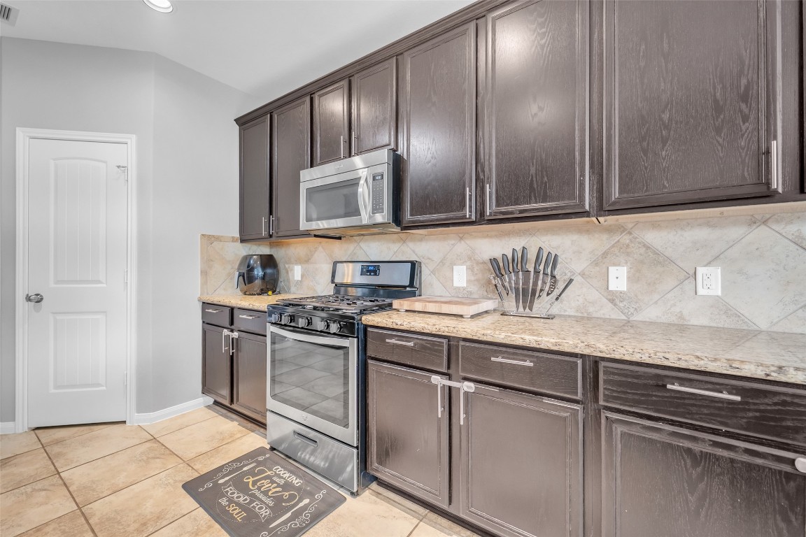 1230 Maple Ace Drive Katy, TX 77493 - Photo 10 of 40 This kitchen features dark wood cabinets, granite countertops, and stainless steel appliances, including a built-in microwave and gas stove.