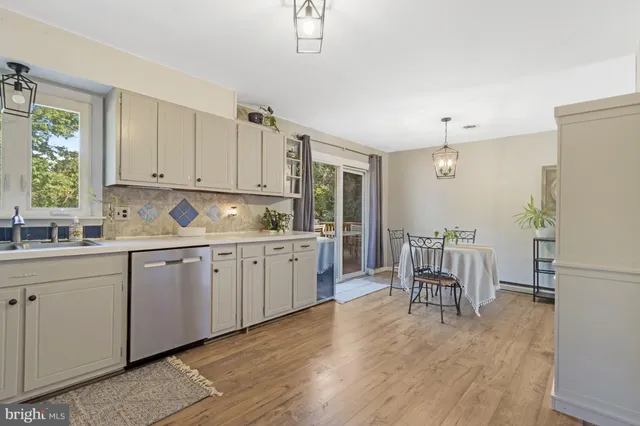 a kitchen with granite countertop a refrigerator a stove a dining table and chairs with wooden floor