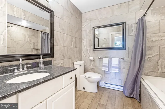 a bathroom with a granite countertop toilet a sink and a mirror