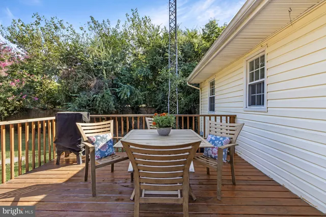 a roof deck with a dining table and chairs with wooden floor