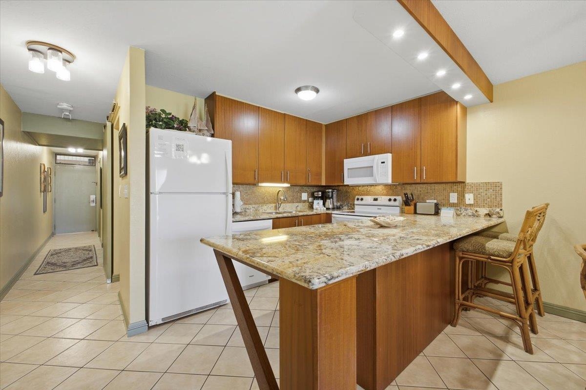 2695 South Kihei Road, Unit 5114 Kihei, HI 96753 - Photo 10 of 47 a kitchen with stainless steel appliances granite countertop a refrigerator a sink a stove and chairs