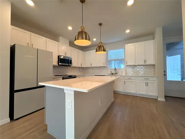 a kitchen with a refrigerator a sink and dishwasher with wooden floor