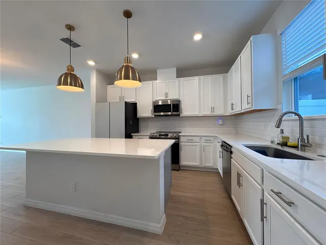 a kitchen with kitchen island granite countertop a sink a counter top space and cabinets