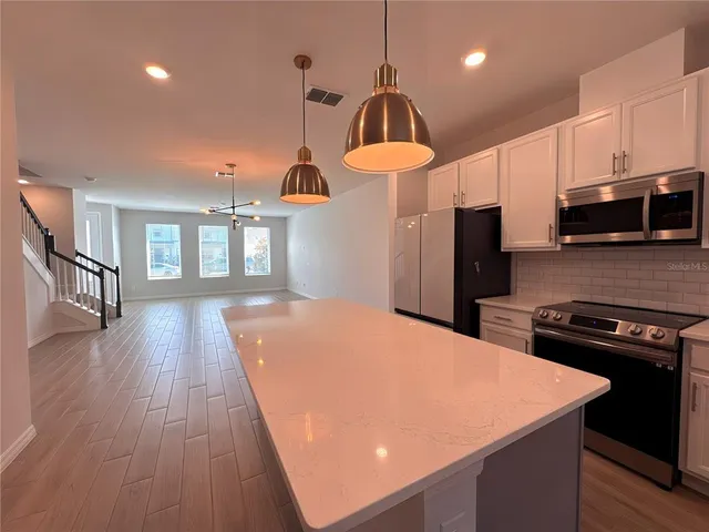 a kitchen with stainless steel appliances a kitchen island hardwood floor sink stove dining table and chairs