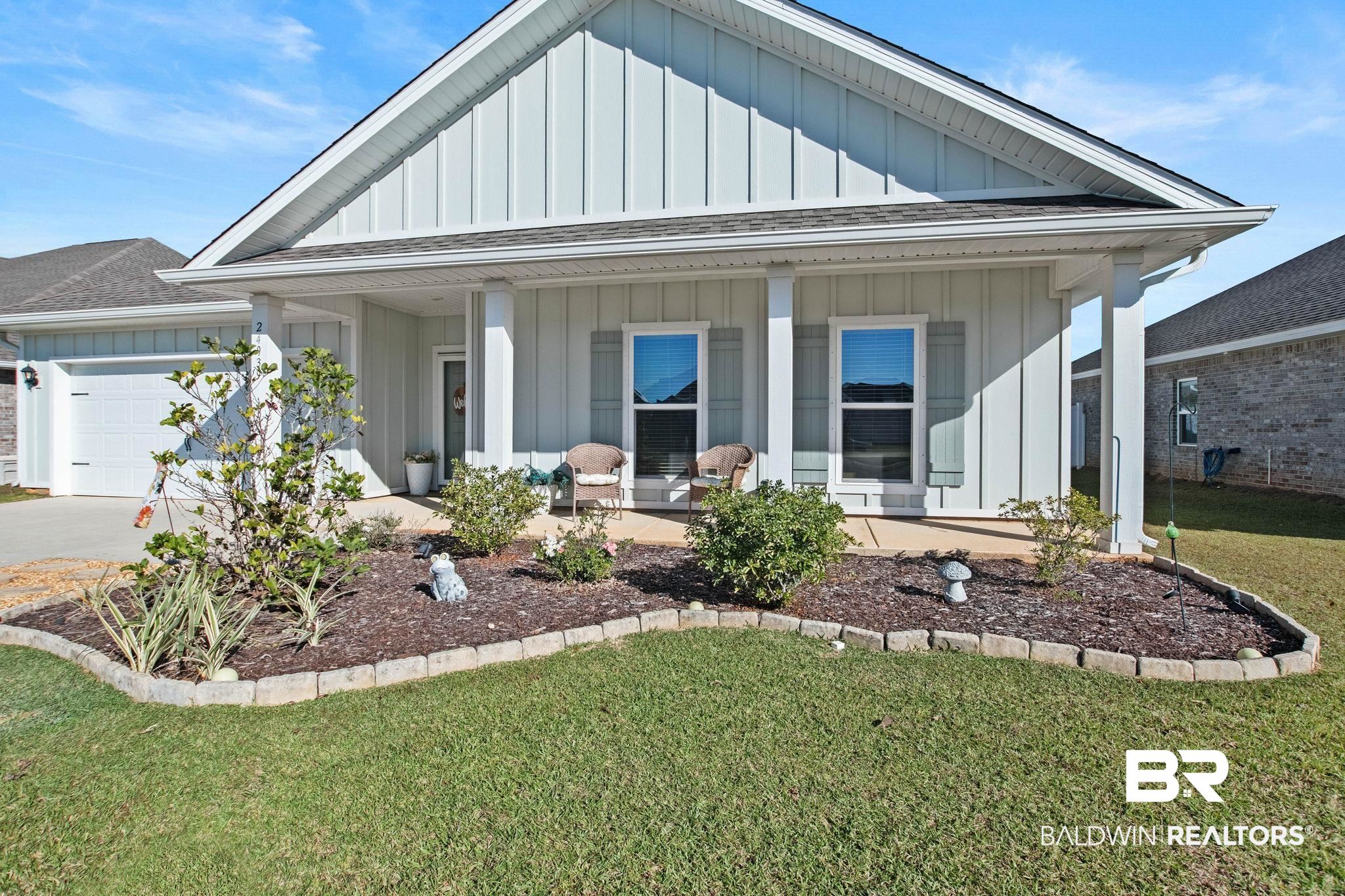 View of front of property with board and batten siding, roof with shingles, a front lawn, a porch, and a garage