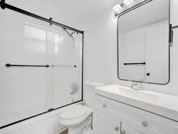 a bathroom with a sink a mirror a toilet and shower