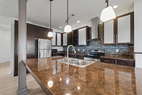 a kitchen with stainless steel appliances granite countertop a sink a stove and a refrigerator