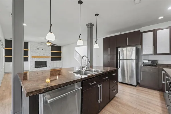 a kitchen with stainless steel appliances granite countertop a sink a refrigerator and a wooden floor